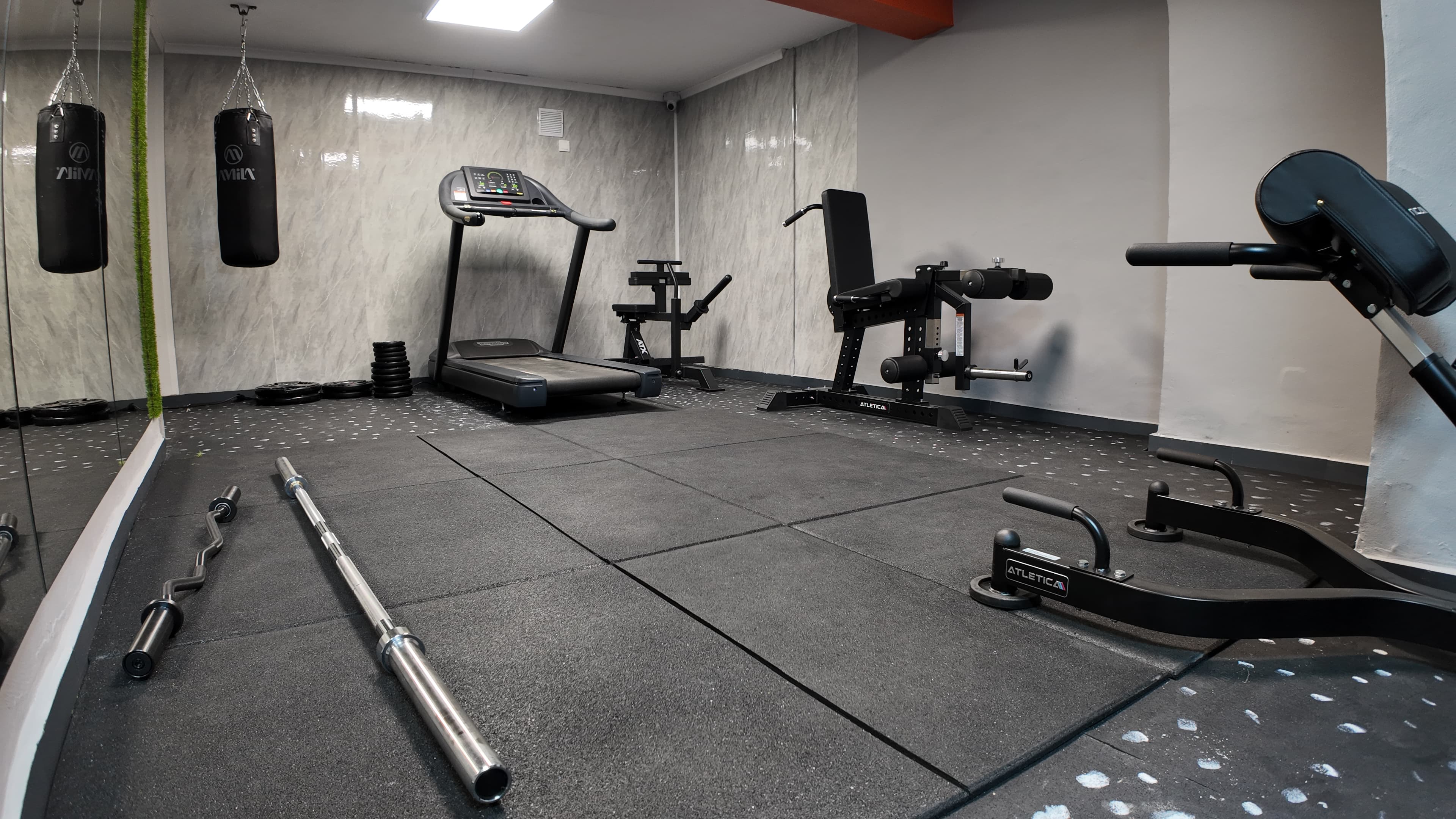 Светла частна зала с power rack, огледало и дъмбели